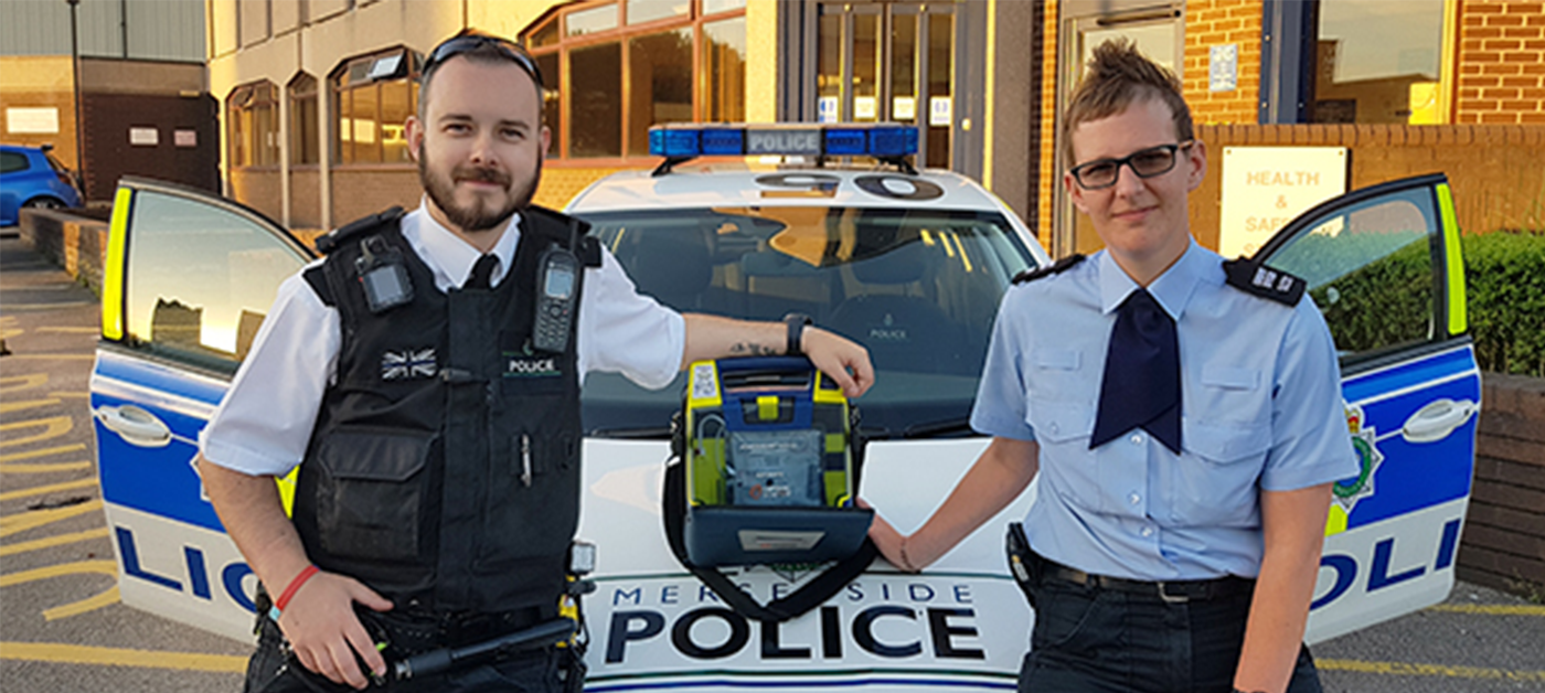Two police officers pose with an AED.