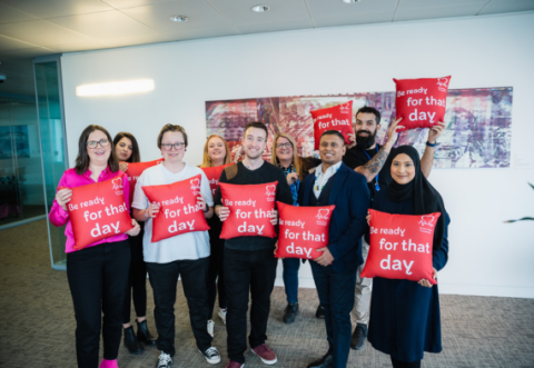 Photo of a group of people holding cushions that read "Be ready for that day."