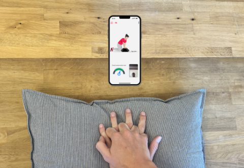 Photo of someone practicing CPR on a pillow with the RevivR app on a smartphone.