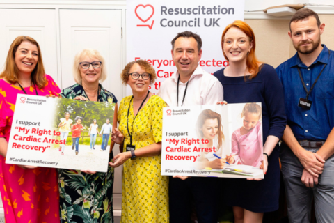 Group of people smiling and holding placards with the My Right to Cardiac Recovery messaging on them 