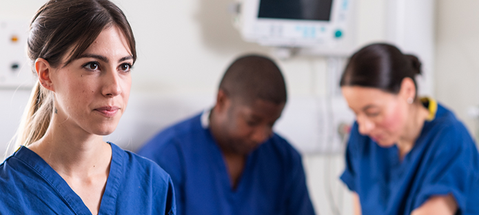 A healthcare professional listens to feedback while her colleagues attend to a patient.