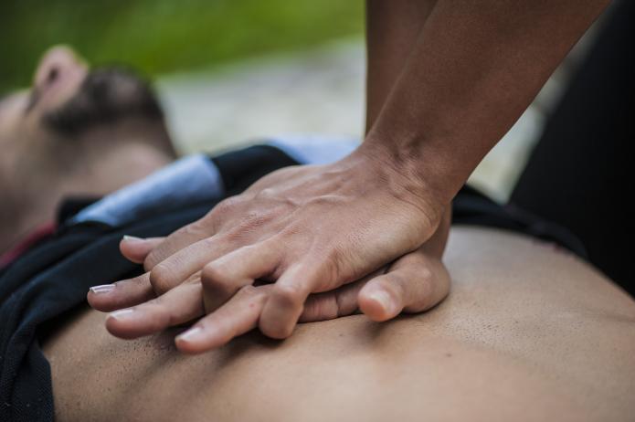 Hands on bare male chest doing CPR compressins