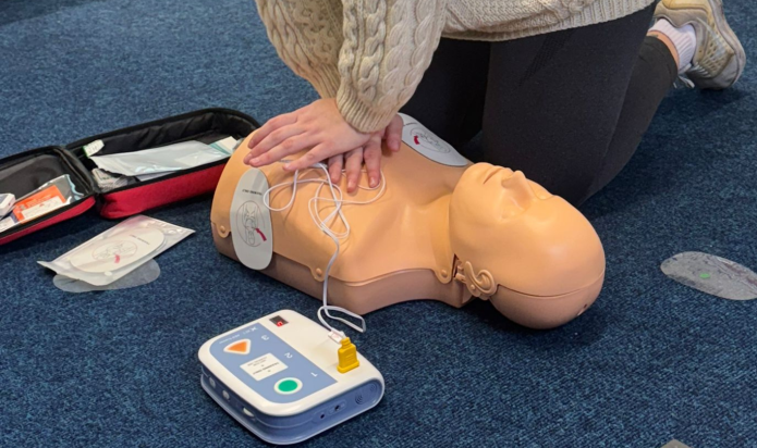 Image of someone practicing CPR and defib use on a manikin